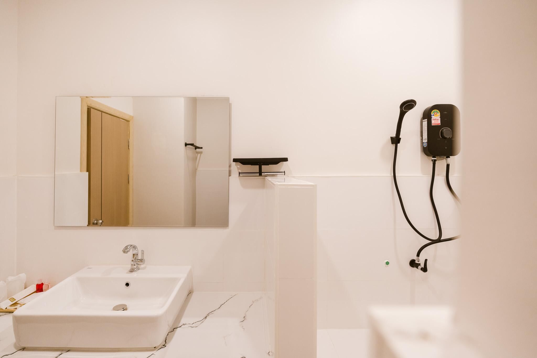 A modern bathroom with a white sink, a mirror, and a wall-mounted hairdryer.