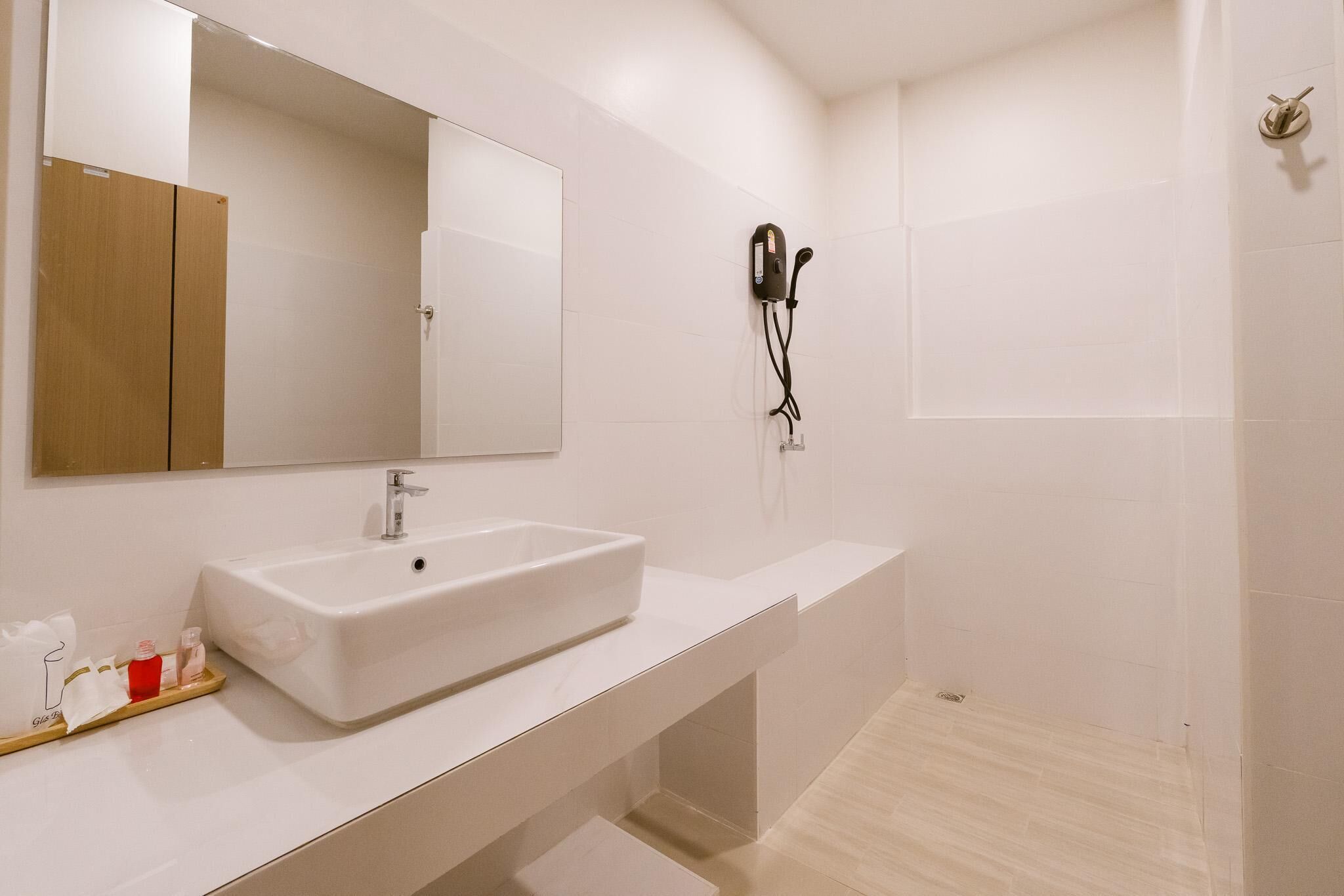 Un baño moderno con un espejo grande, un lavabo blanco y una zona de ducha.