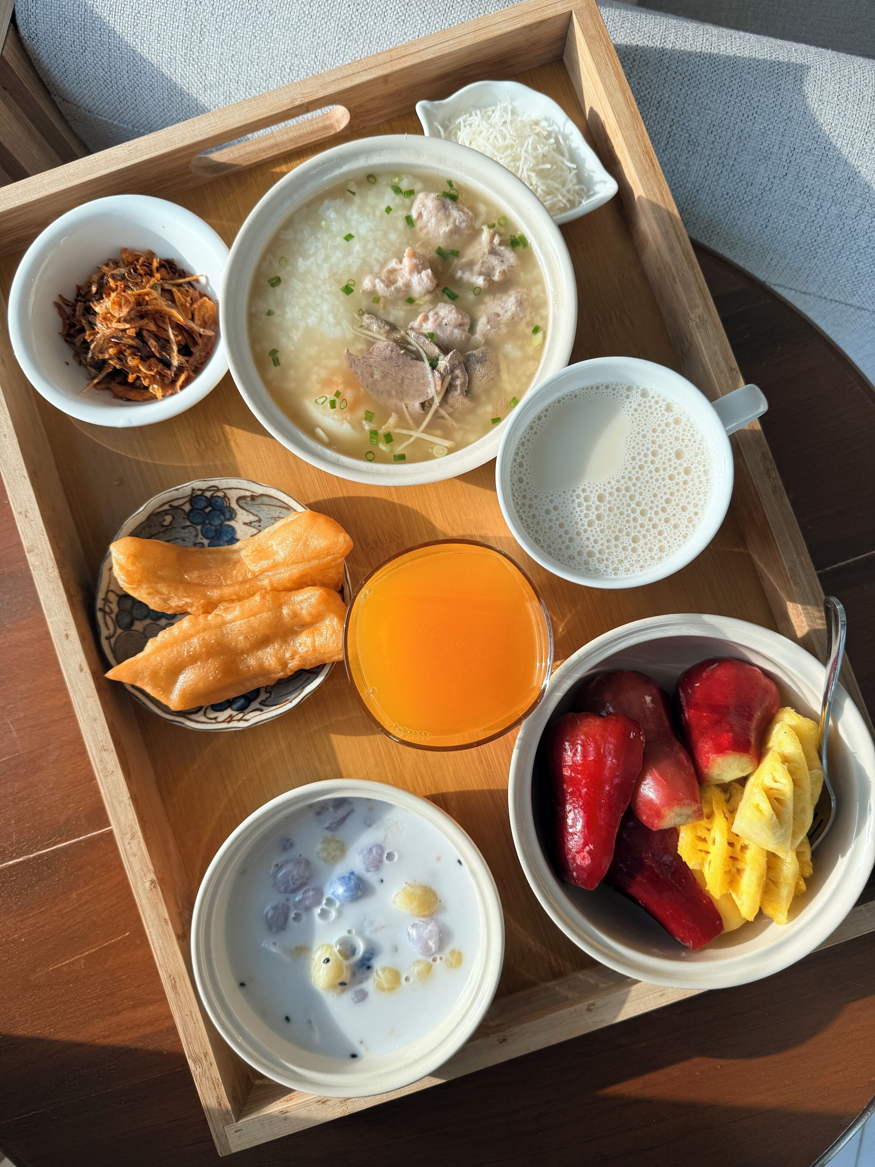 A tray with a bowl of soup, a glass of orange juice, and various side dishes including fruits and a bowl of what appears to be a dessert.