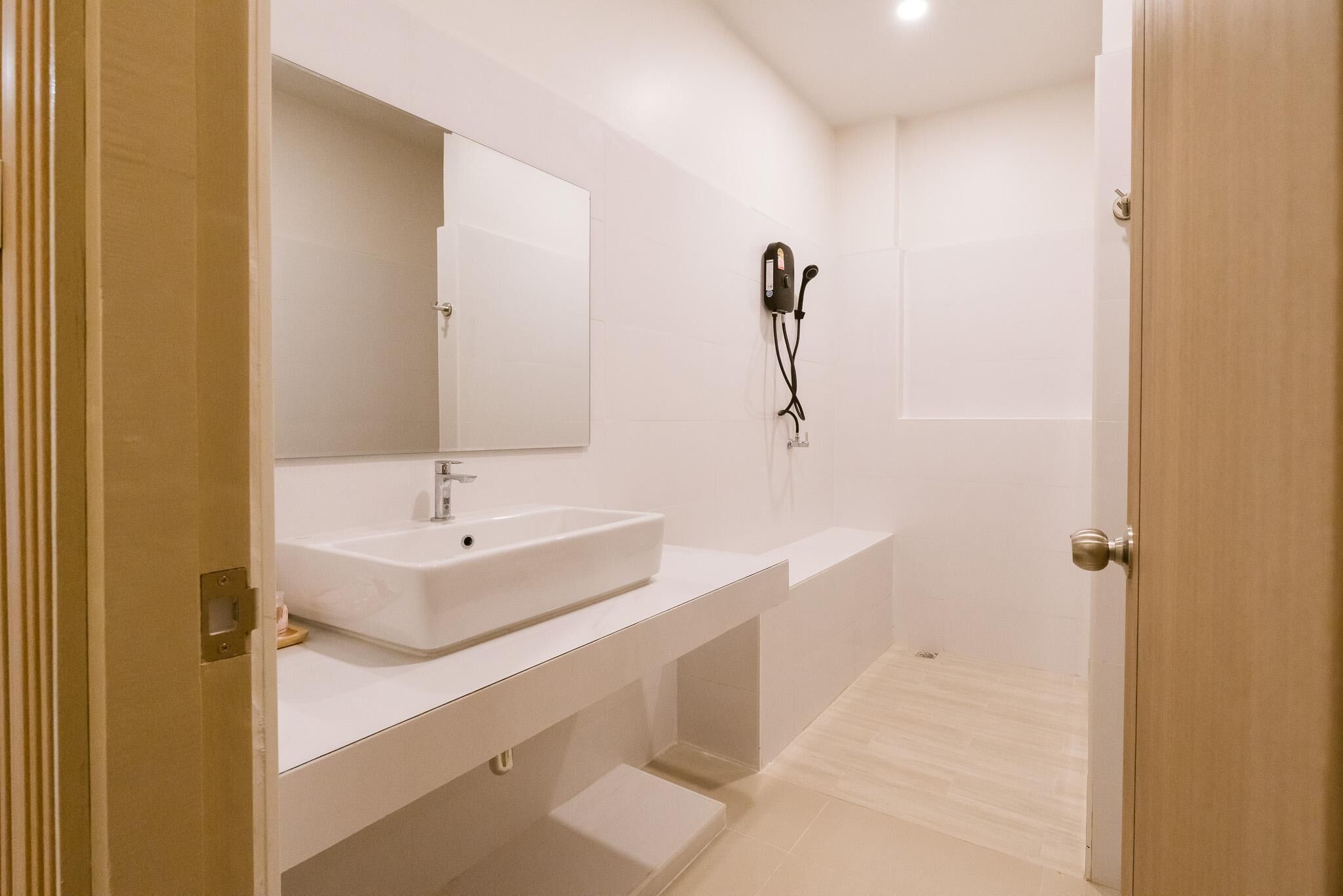 Une salle de bain moderne avec un lavabo blanc, un grand miroir et un espace douche.