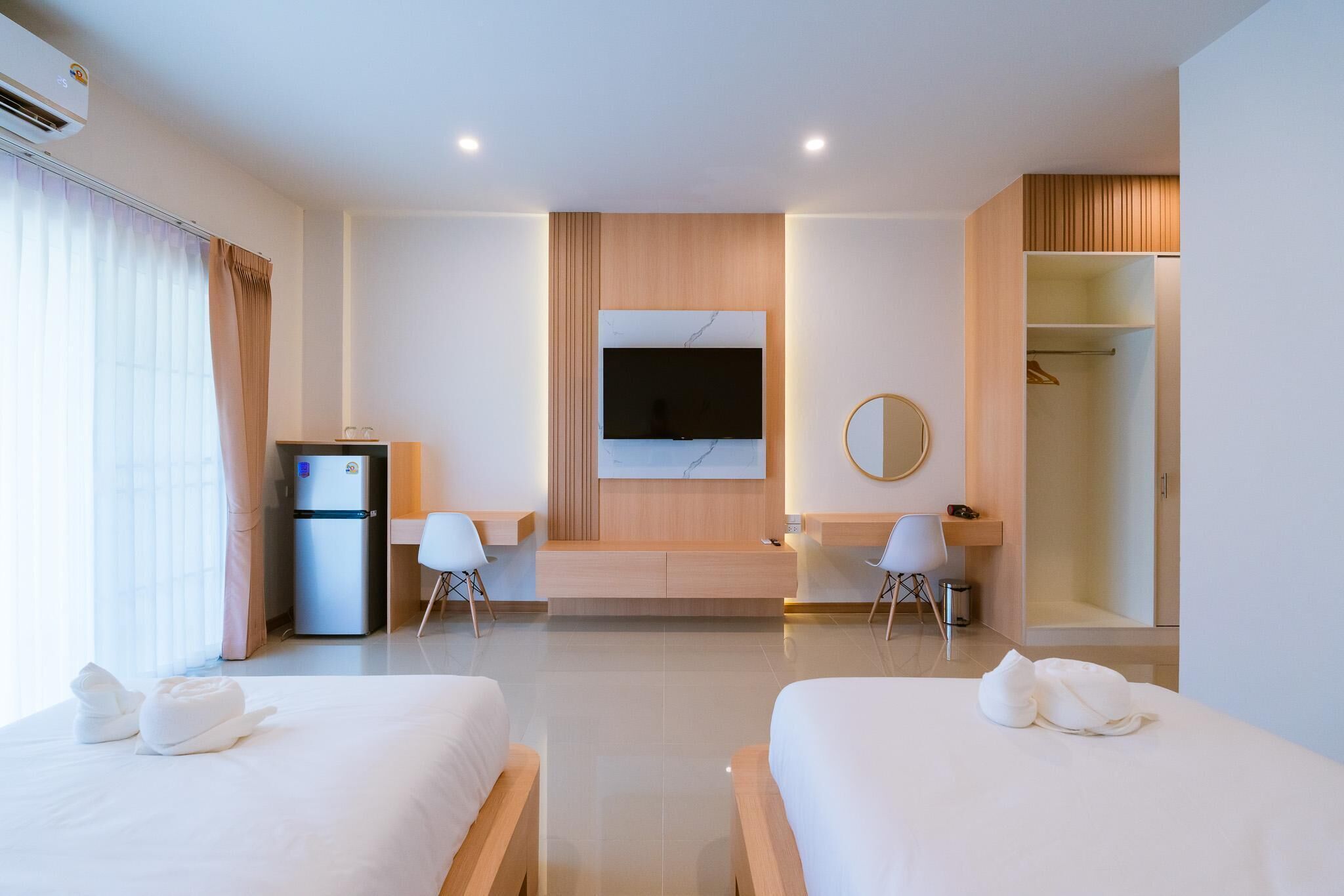 Una habitación de hotel moderna con dos camas, televisión, escritorio y armario.