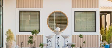 A modern building with large windows, a central circular window, and a decorative fountain.