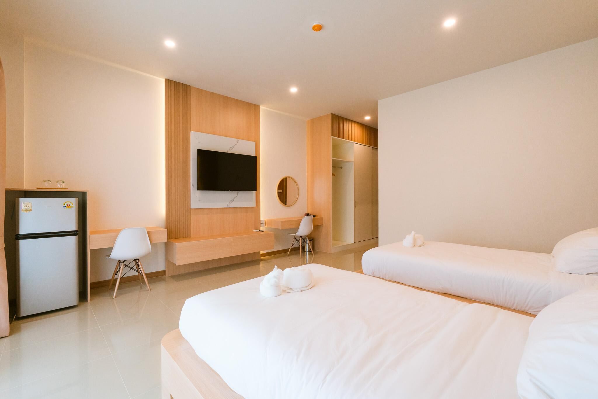 A hotel room with two beds, a desk, a chair, a TV, and a wardrobe.