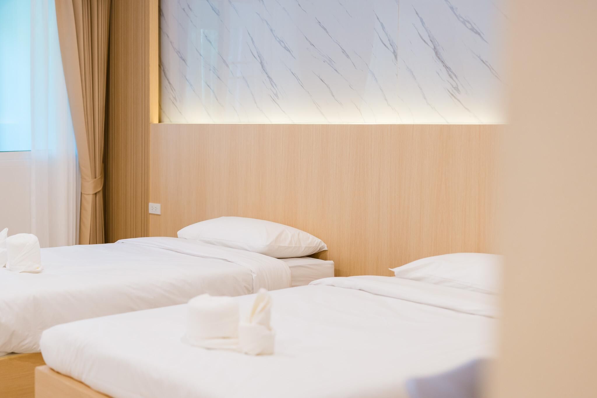 A hotel room with two beds, wooden headboard, and a marble-patterned wall.