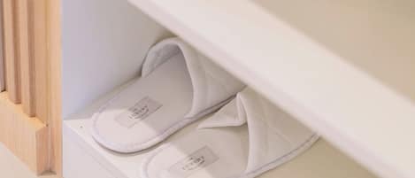 Un par de zapatillas blancas sobre un estante blanco en una habitación con un marco de puerta de madera.