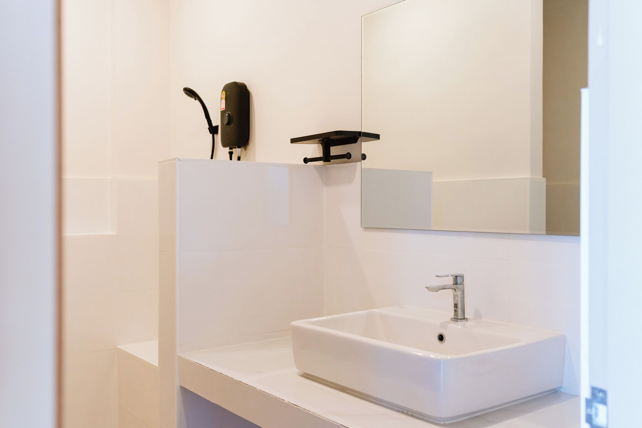 A modern bathroom with a white sink, a mirror, and a soap dispenser.