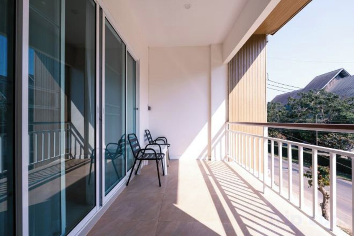 A balcony with a glass door, a small table, and chairs.