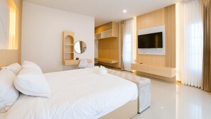 Habitación de hotel moderna con una cama grande, un televisor montado en la pared y estanterías empotradas.