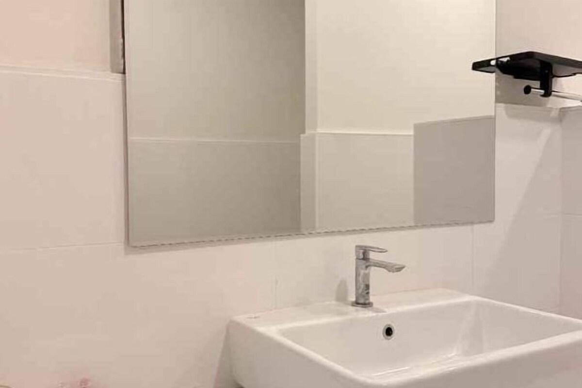 A bathroom with a white sink, a mirror, and a black soap dish.