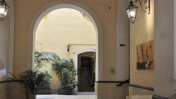 A hallway with an arched entrance, potted plants, and a staircase leading to another area.
