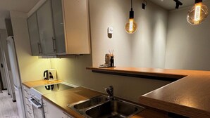 A modern kitchen with a stainless steel sink, wooden countertop, and pendant lighting. - 2-bedroom apartment in Fredrikstad (Østfold)