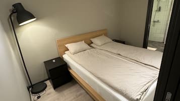 Una camera da letto con un letto, un comodino, una lampada e una porta che dà su un bagno.