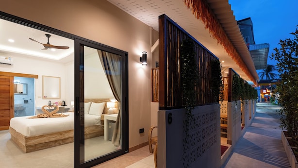 A modern hotel room with a sliding glass door leading to a balcony, a ceiling fan, and a bed with a heart-shaped decoration. - Eden Extend Fisherman Village (Koh Samui)