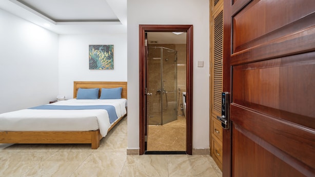 Ein Hotelzimmer mit einem hölzernen Bett, einer Duschabtür aus Glas und einem Holzschrank.