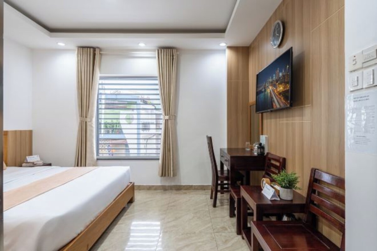A hotel room with a bed, a desk, and a TV.