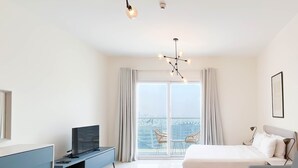 Ein modernes Hotelzimmer mit einem großen Bett, einem Schreibtisch mit Fernseher, einer Couch und einem Balkon mit Blick auf die Stadt.