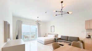 Ein modernes Hotelzimmer mit einem großen Bett, einer Sitzecke, einem Esstisch und einem Balkon mit Blick auf die Stadt.