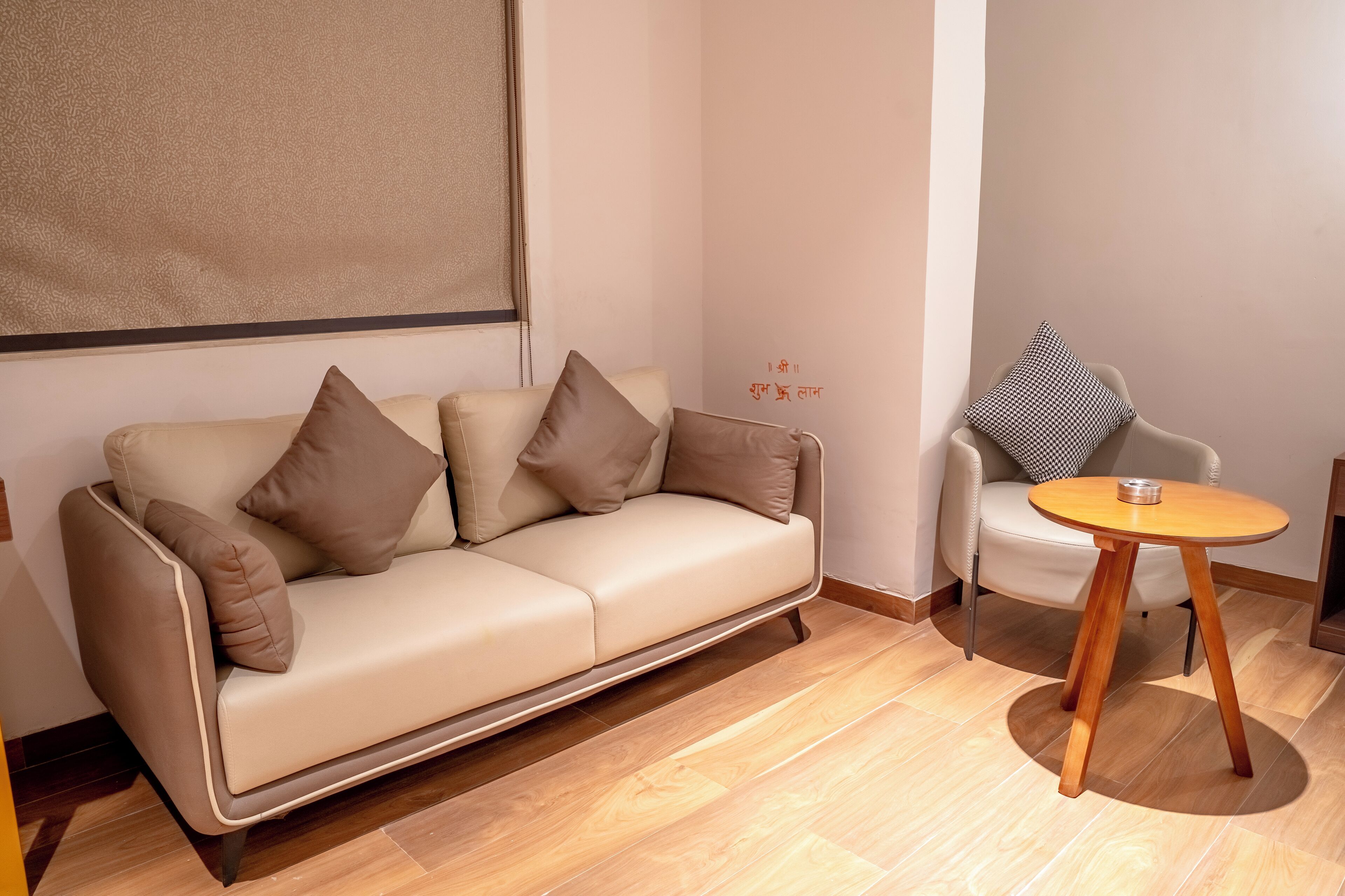 Un salon moderne avec un canapé beige, une table basse ronde en bois et un fauteuil blanc agrémenté d’un coussin à motifs.