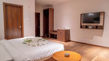 Una habitación de hotel moderna con una cama bien hecha, una mesita de noche de madera, un televisor montado en la pared y un armario de madera.