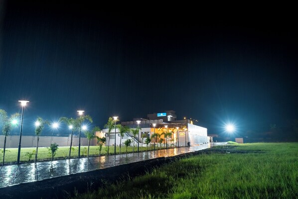 Un edificio moderno con techo plano, rodeado por un canal de agua y palmeras.