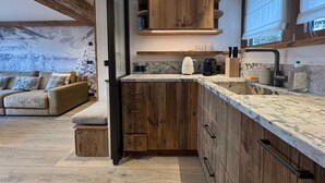 Una cocina moderna con armarios de madera, encimera de mármol y horno empotrado.