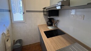 A compact kitchen with a microwave, a coffee maker, and a wooden countertop.