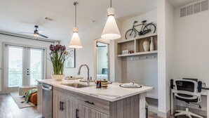 Una cocina moderna con una isla central, lavavajillas y una bicicleta colgada en la pared.