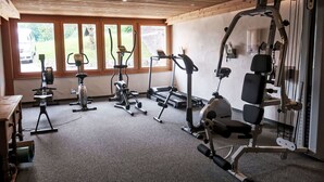 A gym with various exercise machines, large windows, and a wooden ceiling. - Beautiful apartment for 6 people with WIFI, TV, balcony and panoramic view (Les Diablerets)