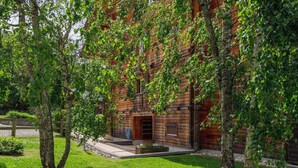 A rustic wooden building with a central entrance, surrounded by a well-maintained lawn and trees. - Beautiful apartment for 6 people with WIFI, TV, balcony and panoramic view (Les Diablerets)