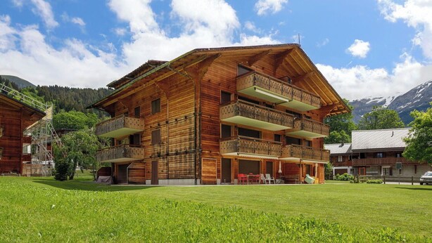 A wooden chalet with multiple balconies, a covered outdoor seating area, and a mountainous backdrop. - Beautiful apartment for 6 people with WIFI, TV, balcony and panoramic view (Les Diablerets)