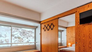 Une chambre moderne dotée d’une grande fenêtre, d’une armoire en bois et d’un lit avec une tête de lit.