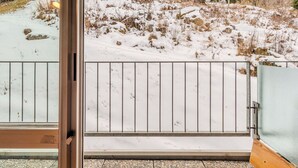 Un espace extérieur enneigé, avec un portail en métal, un bâtiment doté d’un toit en pente et un télésiège en arrière-plan.