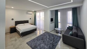 Een moderne slaapkamer met een bed, een bank, een kleine tafel en een televisie.