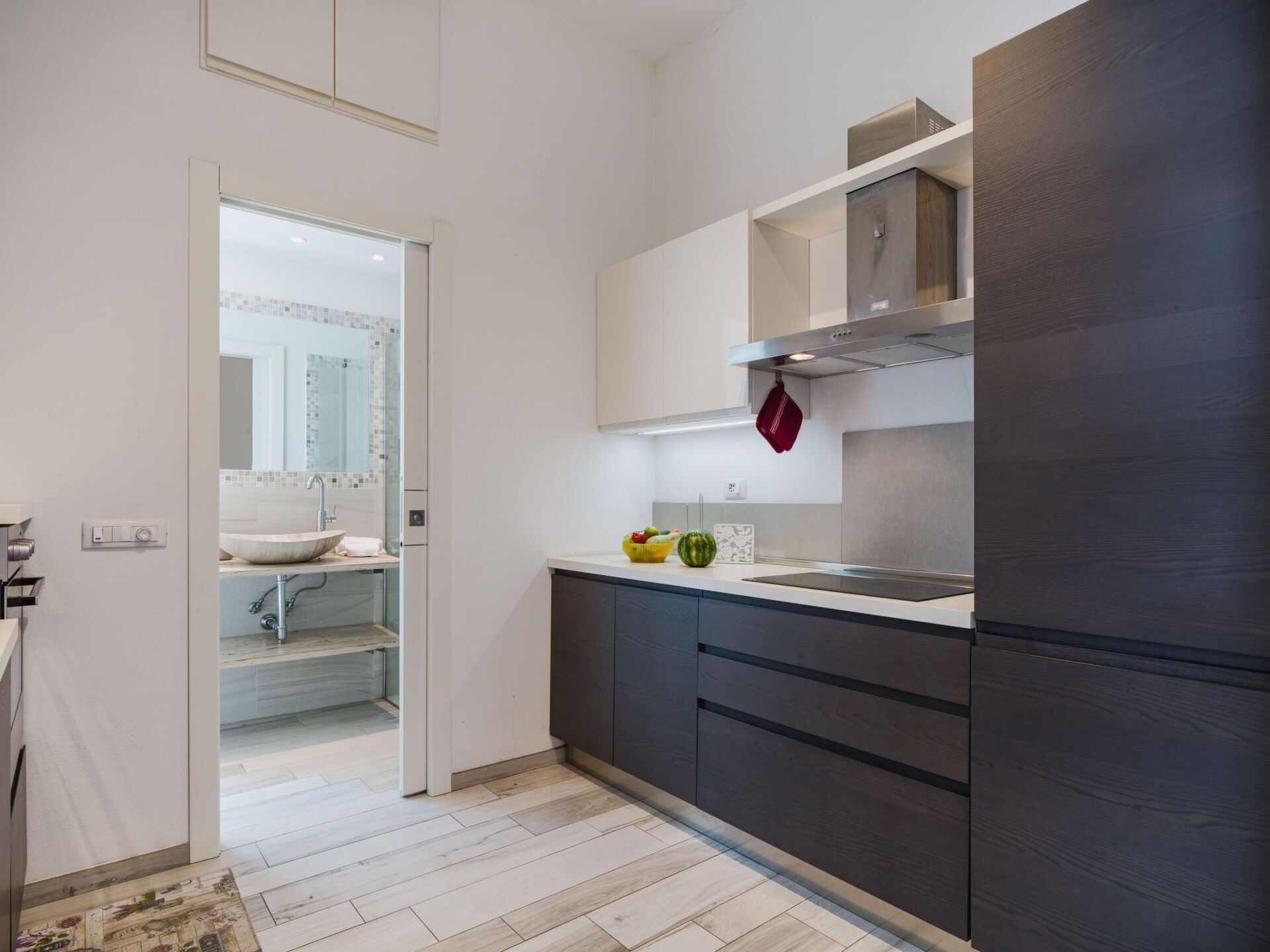 A modern kitchen with dark cabinetry, a stainless steel range hood, and a white countertop.
