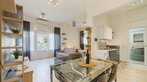 A modern apartment with a glass dining table, a sofa, a kitchen area, and a laundry room. - Cosy apartment for 4 people with A/C, WIFI, TV, patio and pets allowed (Camaiore)
