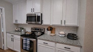 A kitchen with white cabinets, a stainless steel microwave, a stove, and a toaster. - Crew Base | Bunk Beds •Pool Table •Parking• Yard (Frisco)