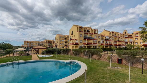A hotel with a swimming pool, multiple balconies, and a well-maintained lawn. - Family Apartment With Amenities (Ayamonte)