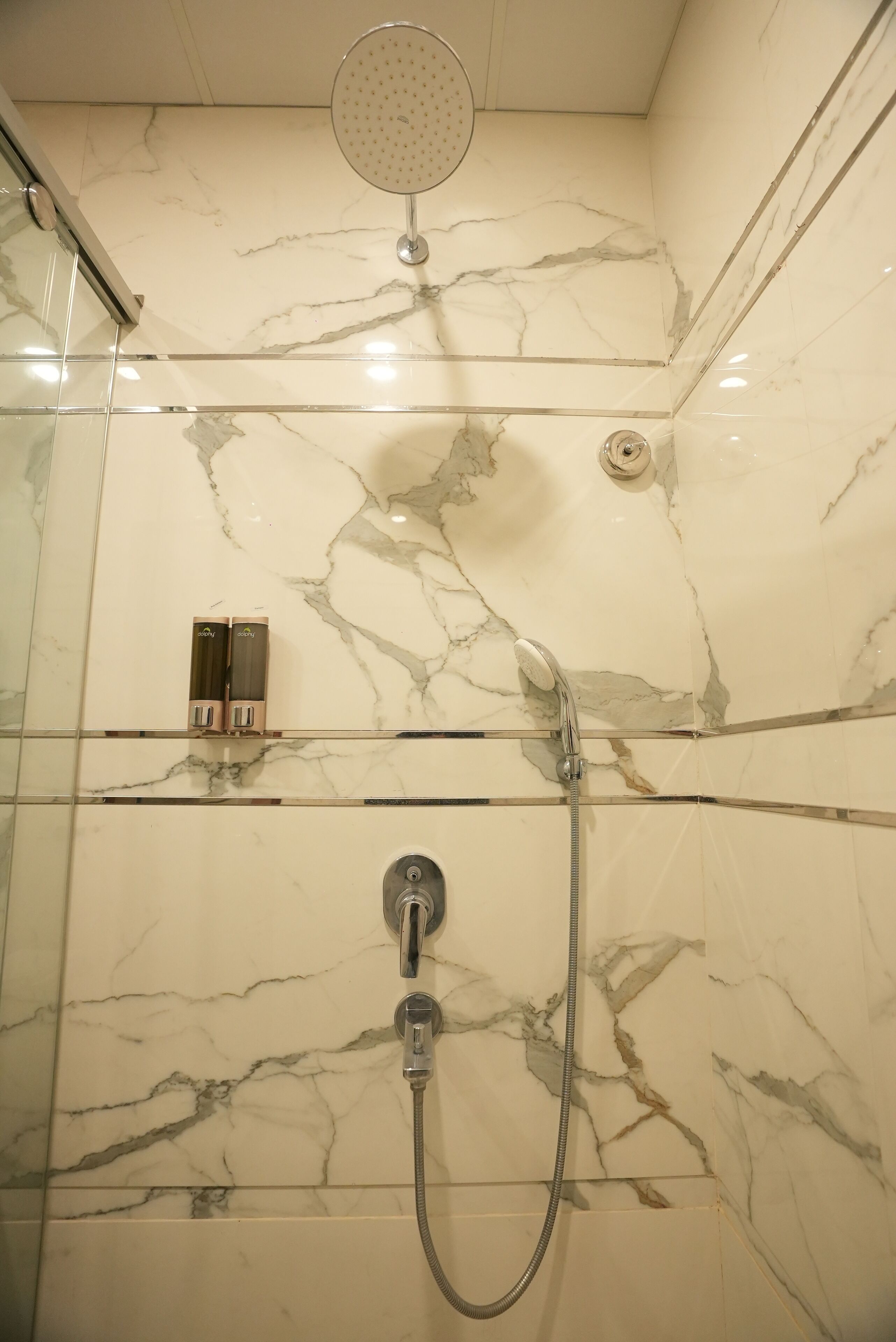 A shower with a handheld showerhead and a wall-mounted faucet.