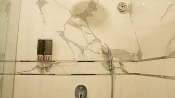 A shower with a handheld showerhead and a wall-mounted faucet.