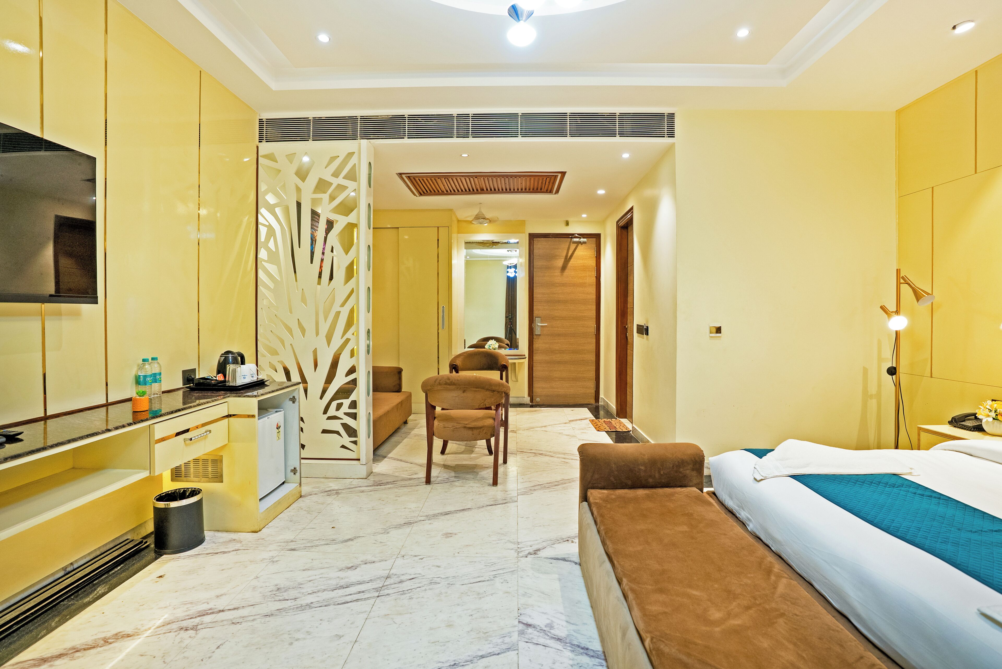 A hotel room with a bed, a desk, a chair, a TV, and a bathroom.