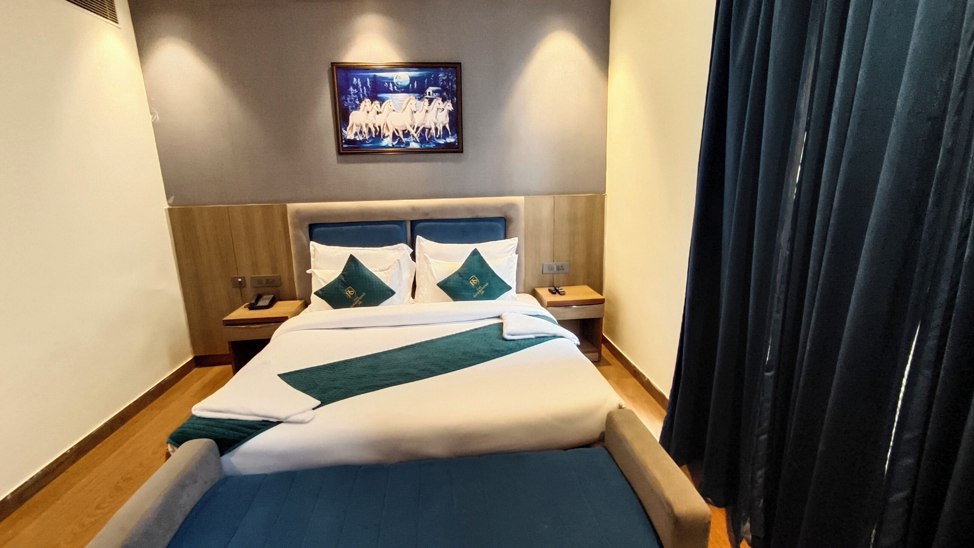 A hotel room with a bed, two nightstands, a framed picture on the wall, and a curtain.