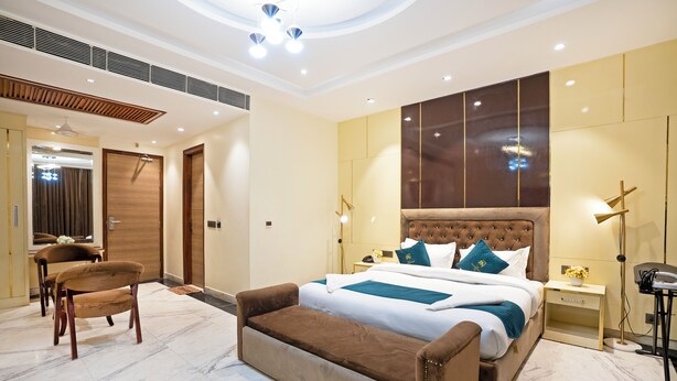 A modern bedroom with a large bed, a sofa, and a desk. - The Riverstone Inn - Near India Expo Centre & Mart, Greater Noida (Greater Noida)