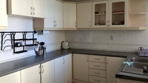 Een keuken met witte kastjes, een zwart aanrecht en een spoelbak.