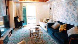 A living room with a sofa, a TV, and a patterned rug. - Premium Swiss Residence Agouza (Giza)