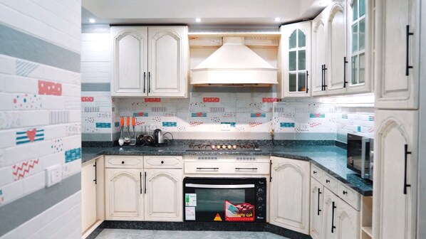 A kitchen with white cabinets, a stove, and a microwave.