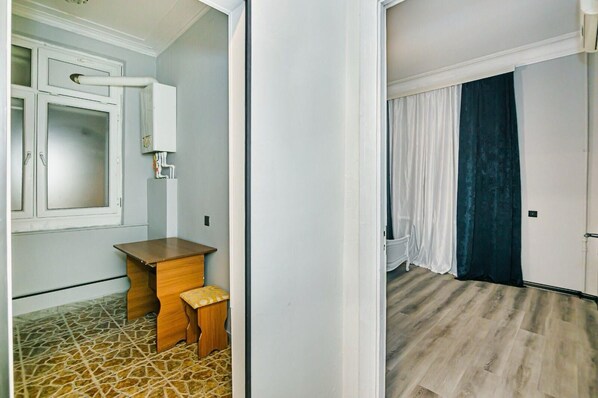 A room with a wooden desk, a small stool, a white cabinet, and a tiled floor.