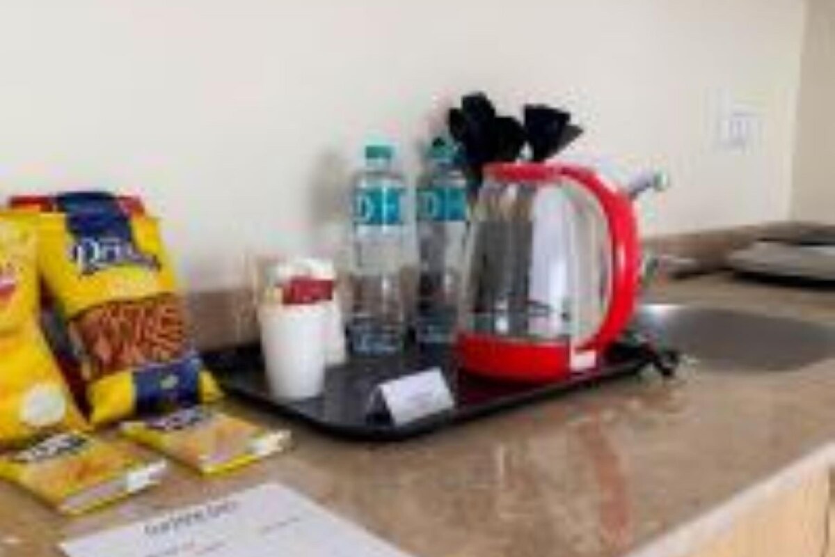 Una encimera de cocina con una cafetera, una botella de agua, una bolsa de papas y un menú.