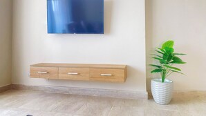 Ein Flachbildfernseher ist an einer Wand oberhalb einer Holzkombination mit Schubladen angebracht.