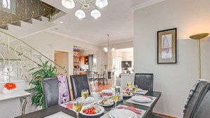 A dining area with a long table set for six, surrounded by chairs. A staircase with a decorative railing is visible in the background. - Villa Clio, with Mountain view (kalyves Armenoi)