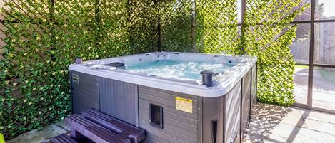 A hot tub with steps and a warning label, surrounded by a lattice fence and large windows.